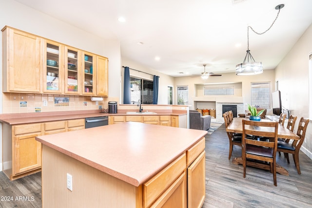 kitchen with a sink, stainless steel dishwasher, wood finished floors, and light brown cabinetry