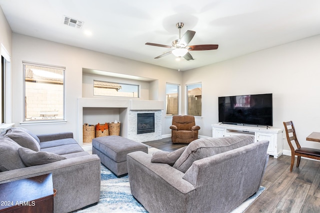 living room with visible vents, baseboards, a glass covered fireplace, and wood finished floors