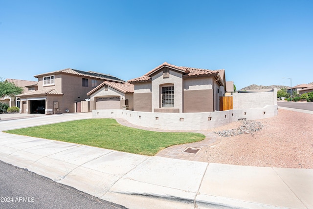 mediterranean / spanish-style house with stucco siding, fence, concrete driveway, a front yard, and a tiled roof