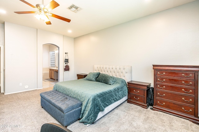 bedroom with visible vents, light carpet, arched walkways, ensuite bath, and a ceiling fan