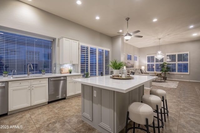 kitchen with open floor plan, light countertops, ceiling fan with notable chandelier, a sink, and dishwasher