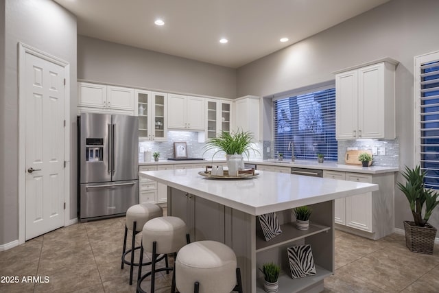 kitchen featuring white cabinetry, light countertops, open shelves, a kitchen island, and appliances with stainless steel finishes