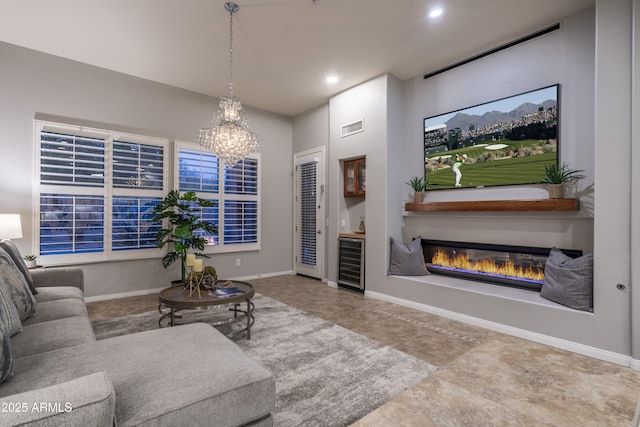 living area with a chandelier, a glass covered fireplace, beverage cooler, visible vents, and recessed lighting