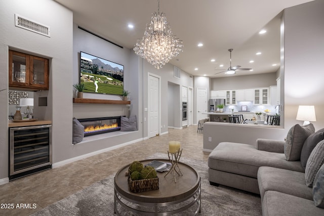 living area featuring visible vents, ceiling fan with notable chandelier, recessed lighting, and beverage cooler