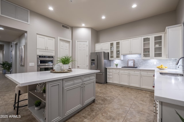 kitchen with a sink, decorative backsplash, visible vents, and appliances with stainless steel finishes