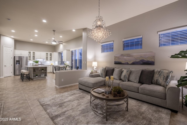 living area with light tile patterned floors, baseboards, recessed lighting, and ceiling fan with notable chandelier