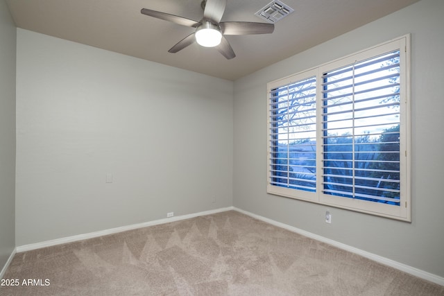 carpeted spare room featuring baseboards, visible vents, and a ceiling fan