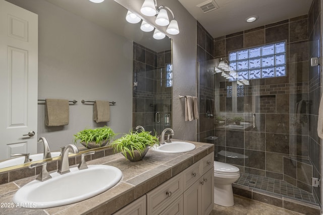 bathroom with toilet, a sink, a stall shower, and visible vents