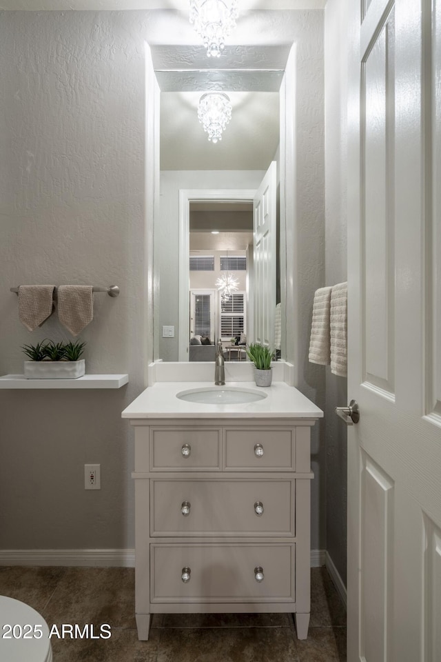 bathroom featuring baseboards, an inviting chandelier, tile patterned floors, and vanity