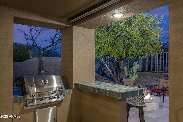 view of patio / terrace featuring a grill, a fire pit, a fenced backyard, and exterior kitchen