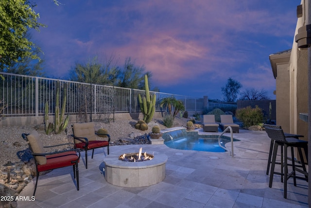 pool at dusk featuring an outdoor fire pit, a fenced backyard, and a patio