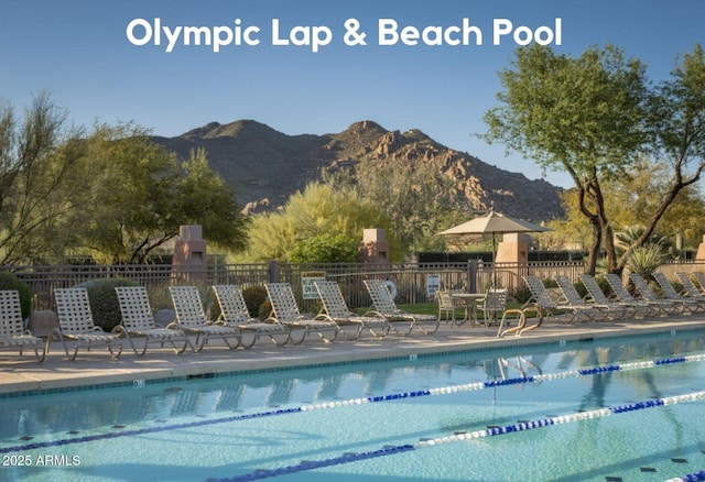 community pool featuring a mountain view, fence, and a patio