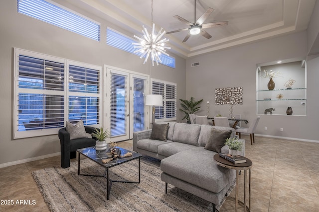 living room featuring a raised ceiling, tile patterned floors, baseboards, and visible vents