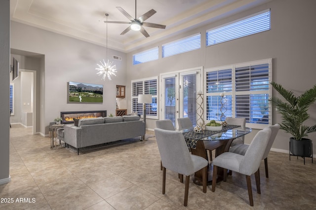 dining room with ceiling fan with notable chandelier, baseboards, a raised ceiling, light tile patterned flooring, and visible vents