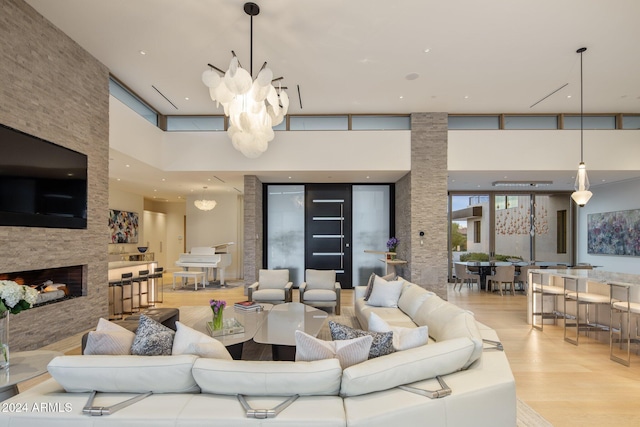 living room featuring light hardwood / wood-style flooring, a fireplace, a high ceiling, and a chandelier