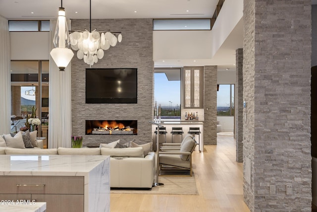 living room featuring a fireplace, a high ceiling, light wood-type flooring, and a chandelier