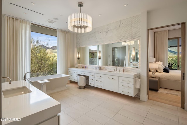 bathroom with a washtub, vanity, a healthy amount of sunlight, and an inviting chandelier