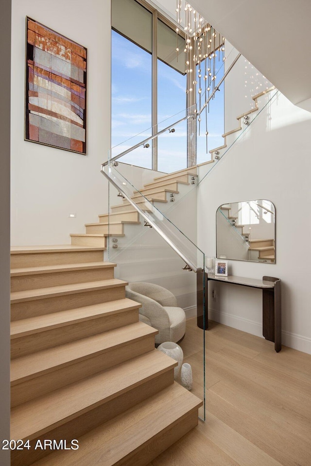 stairway with wood-type flooring and a chandelier