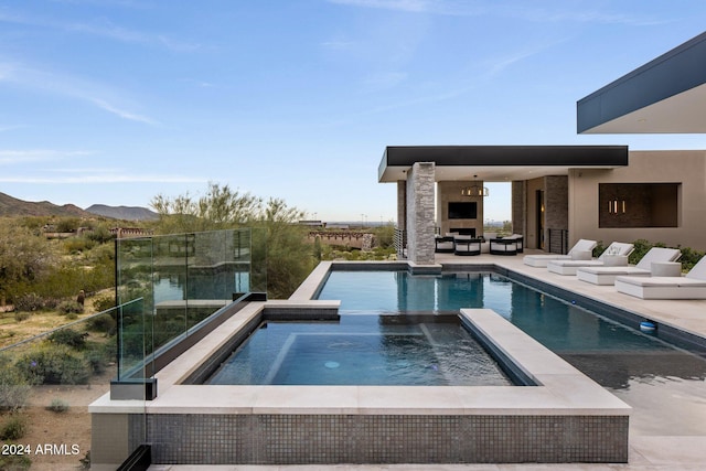 view of swimming pool with a mountain view and exterior fireplace