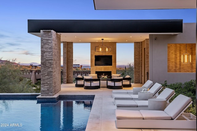 pool at dusk with an outdoor living space with a fireplace and a patio area