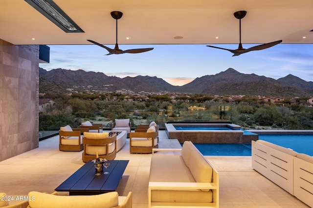 view of patio featuring a mountain view, a swimming pool with hot tub, and an outdoor living space with a fire pit