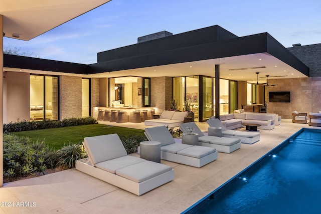 view of pool featuring ceiling fan, exterior kitchen, a patio, and an outdoor fireplace