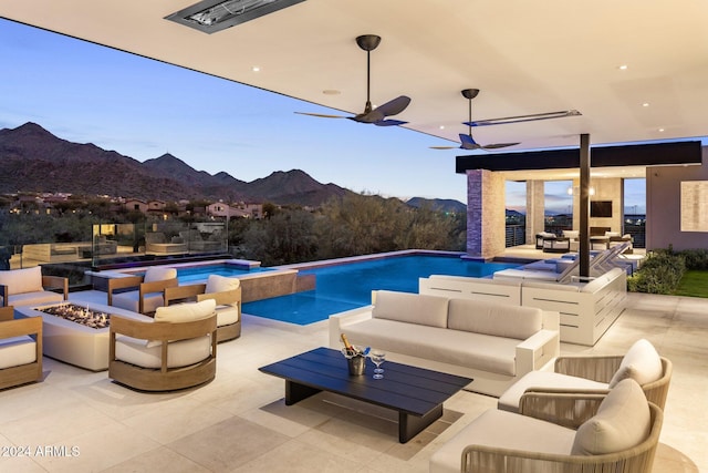 view of pool with a mountain view, a jacuzzi, a patio, and an outdoor living space with a fire pit