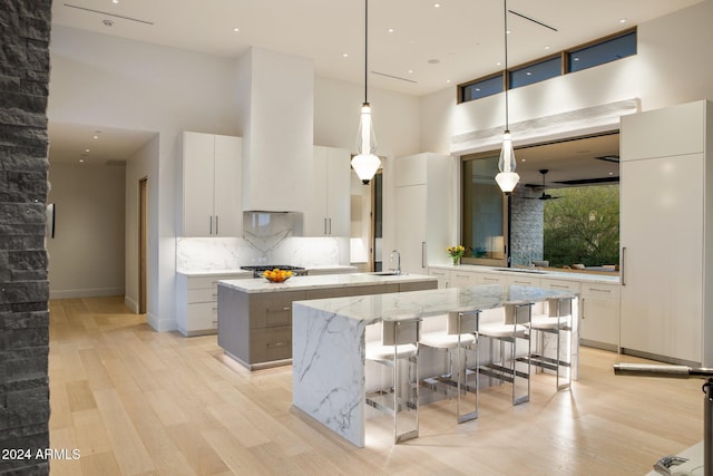 kitchen with white cabinetry, a large island, a towering ceiling, and pendant lighting