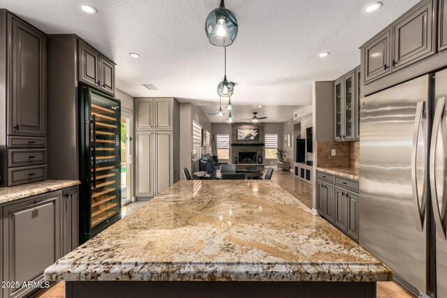 1751 W Mulberry Dr, Chandler, AZ 85286 - kitchen featuring stainless steel refrigerator, wine cooler, a kitchen island, a fireplace, and glass insert cabinets