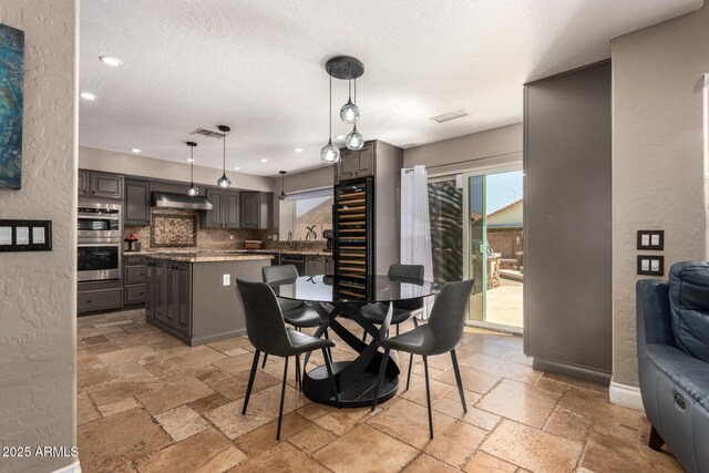 1751 W Mulberry Dr, Chandler, AZ 85286 - dining space featuring stone tile flooring, wine cooler, a textured ceiling, and recessed lighting