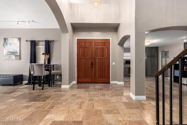 1751 W Mulberry Dr, Chandler, AZ 85286 - foyer entrance with arched walkways, stone tile flooring, a high ceiling, a textured wall, and a textured ceiling