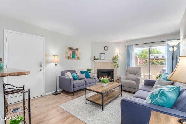 living room featuring a tiled fireplace and light wood-type flooring