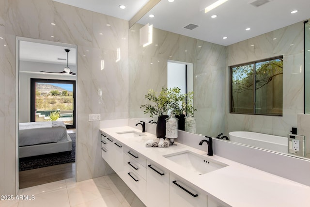 ensuite bathroom featuring a sink, visible vents, and tile walls