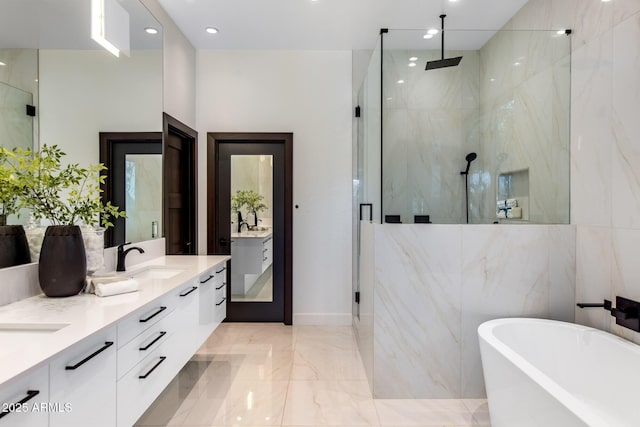 bathroom featuring a sink, a freestanding bath, marble finish floor, a marble finish shower, and double vanity