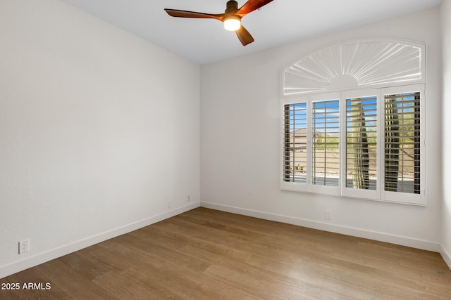 spare room with light wood finished floors, a ceiling fan, and baseboards