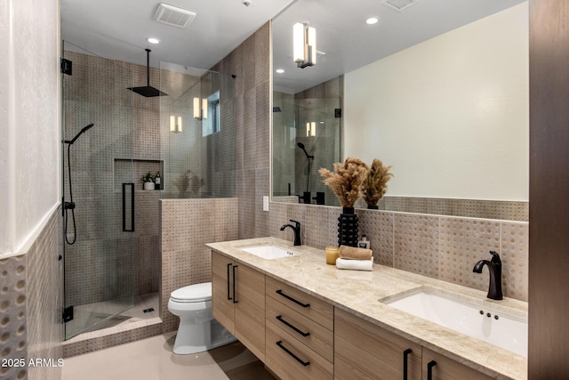 bathroom featuring a stall shower, tile walls, visible vents, and a sink