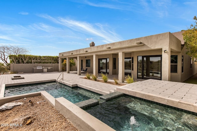 back of property featuring a ceiling fan, an in ground hot tub, fence, a patio area, and stucco siding