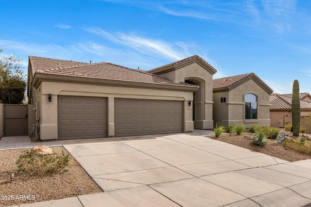 mediterranean / spanish home featuring a garage, concrete driveway, a tiled roof, and stucco siding