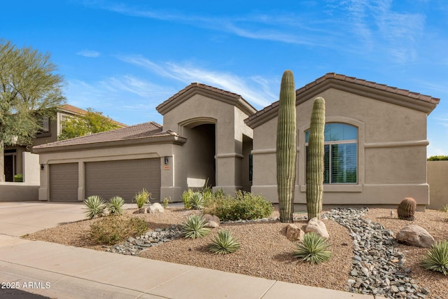 mediterranean / spanish-style house featuring an attached garage, a tile roof, concrete driveway, and stucco siding