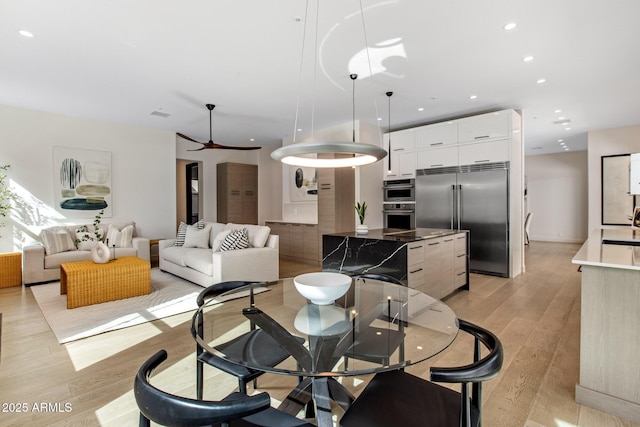 dining area with light wood-type flooring and recessed lighting