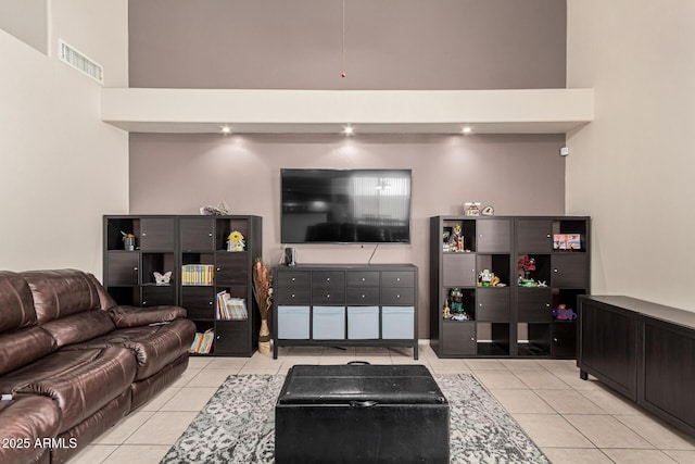 living area with visible vents, light tile patterned floors, and a towering ceiling