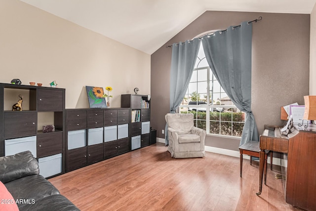 sitting room featuring lofted ceiling, light wood-style flooring, and baseboards