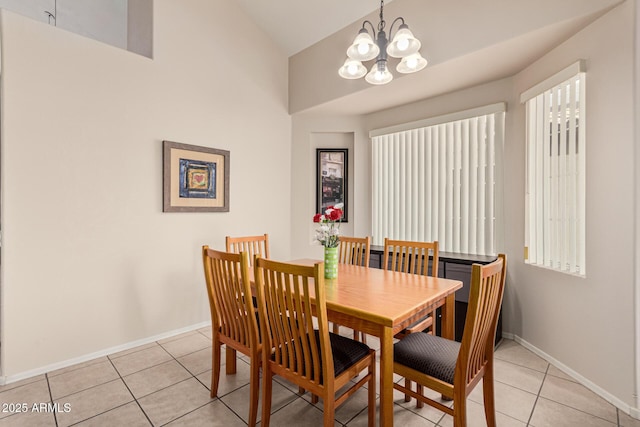 dining area with lofted ceiling, light tile patterned floors, baseboards, and an inviting chandelier