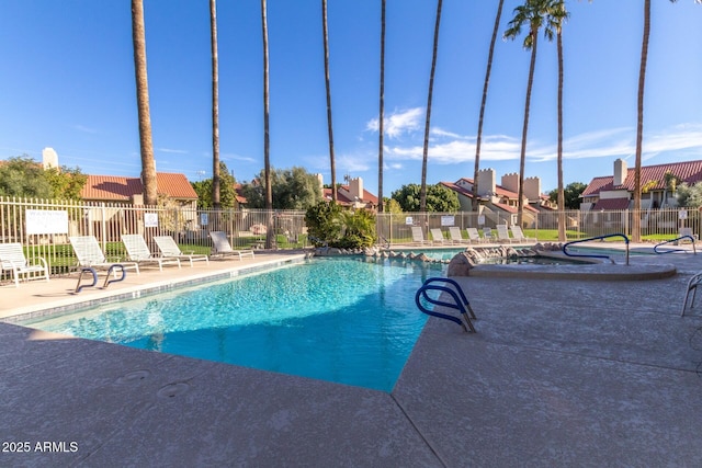 pool with a patio area, fence, and a residential view