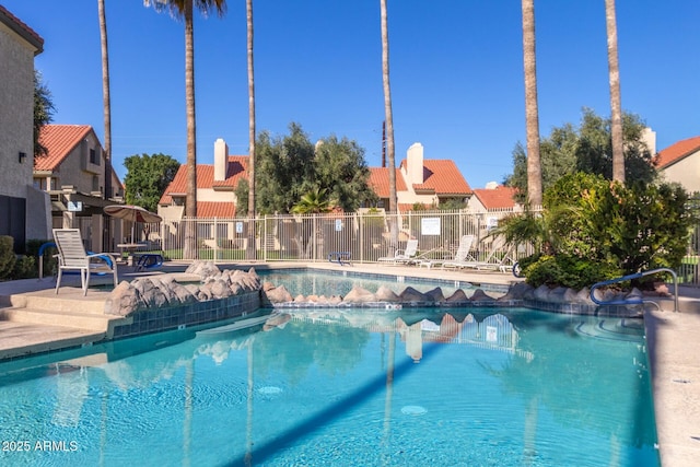 community pool with a residential view, a patio, and fence