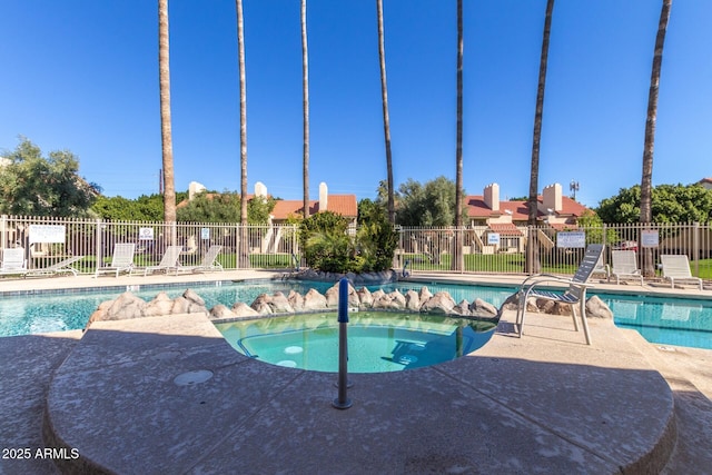 community pool with a community hot tub, a patio, and fence