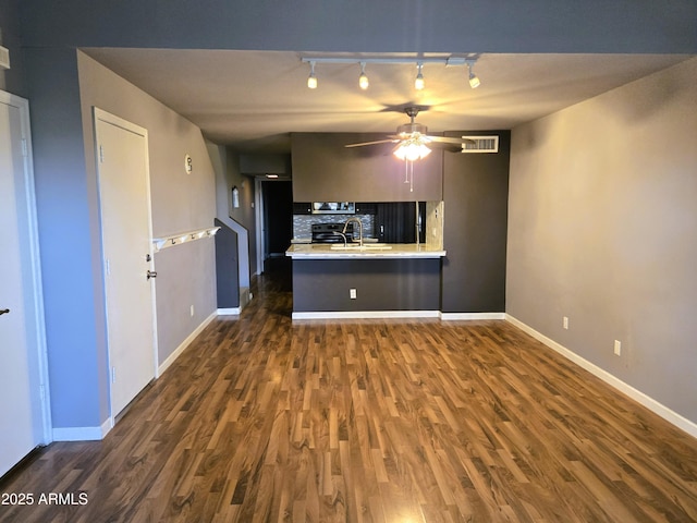 kitchen featuring visible vents, dark wood-type flooring, backsplash, a peninsula, and light countertops