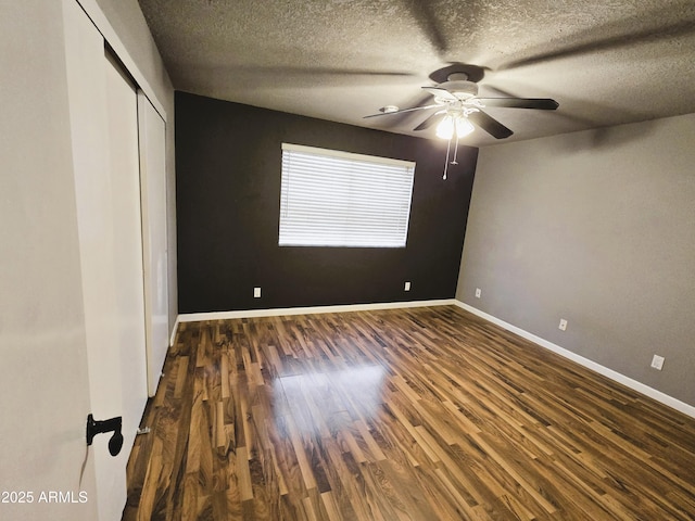 unfurnished bedroom with ceiling fan, baseboards, wood finished floors, a closet, and a textured ceiling