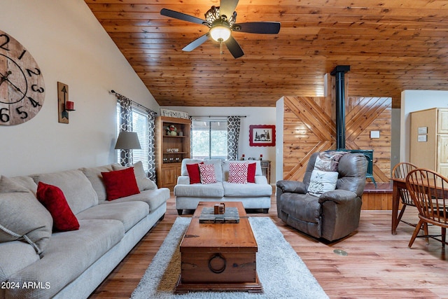 living room featuring wood walls, light hardwood / wood-style floors, ceiling fan, and a wood stove