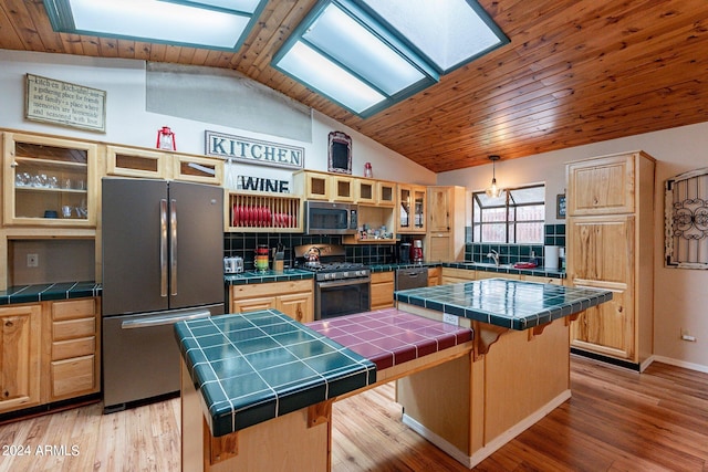 kitchen featuring tile counters, a kitchen bar, a center island, and stainless steel appliances